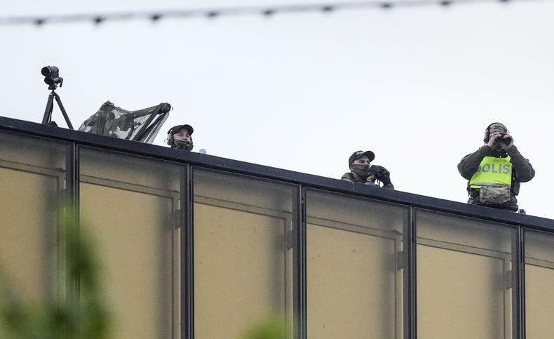 Policías observan desde un techo mientras la gente hace fila para el segundo ensayo general de la primera semifinal del Festival de la Canción de Eurovisión en Malmo, Suecia, el lunes 6 de mayo de 2024. (Foto AP/Martin Meissner)