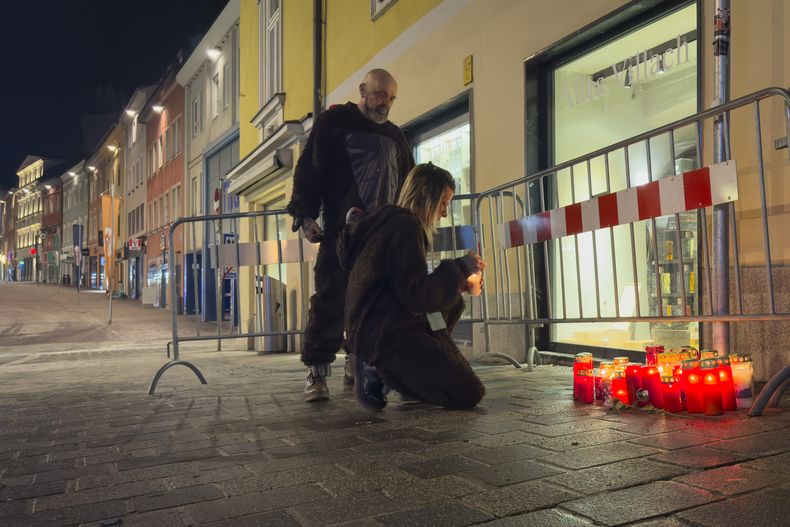 Una persona enciende una vela en el lugar de un apuñalamiento en Villach, Austria, el domingo 16 de febrero de 2025. (AP Foto/Darko Bandic)