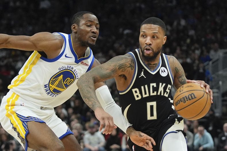 Damian Lillard, de los Bucks de Milwaukee, supera a Jonathan Kuminga, de los Warriors de Golden State, durante la primera mitad del partido de baloncesto de la NBA, el sábado 13 de enero de 2024, en Milwaukee. (AP Foto/Morry Gash)