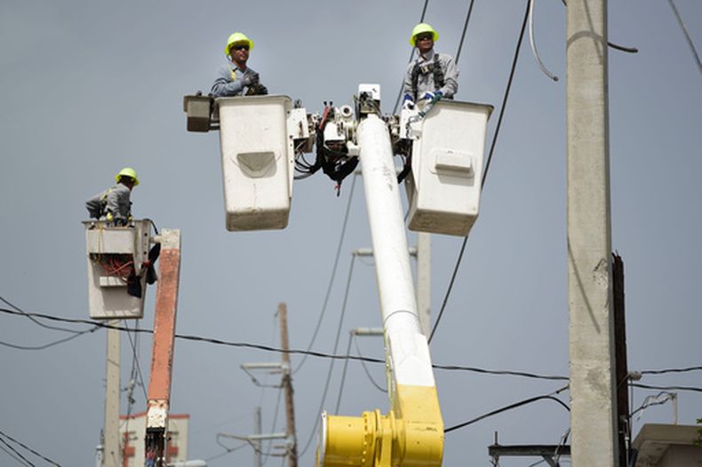 ARCHIVO - Trabajadores de la Autoridad de Energía Eléctrica de Puerto Rico reparan líneas de distribución dañadas por el huracán María en la comunidad de La Cantera, en San Juan, Puerto Rico, el 19 de octubre de 2017. (AP Foto/Carlos Giusti/Archivo)