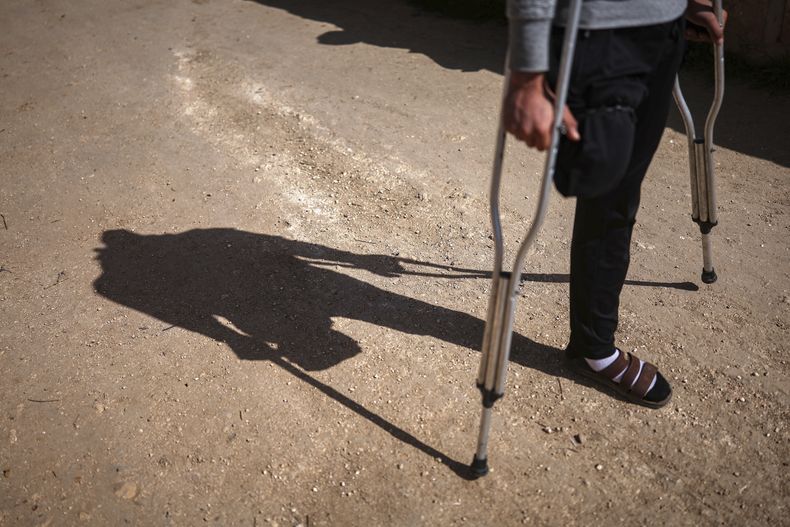 Suleiman Jalil, de 21 años --que perdió una pierna debido a la explosión de una mina terrestre mientras cosechaba aceitunas junto con sus amigos en un campo--, camina afuera de su casa el miércoles 9 de abril de 2025, en el poblado de Qaminas, al este de Idlib, Siria. (AP Foto/Ghaith Alsayed)