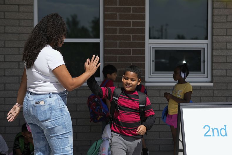 Dylan Martínez-Ramírez, centro, saluda a su maestra Aliah James, izquierda, en su escuela en Aurora, Colorado, el 29 de agosto del 2024. (AP Foto/Godofredo A. Vásquez)