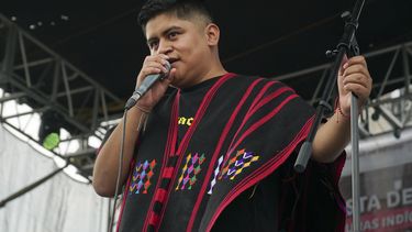 El rapero mexicano-triqui Carlos CGH, vestido con un gabán negro y rojo, una prenda nativa del pueblo triqui en el oeste de Oaxaca, actúa durante una celebración de los pueblos indígenas en el Zócalo de la Ciudad de México, el martes 6 de agosto de 2024. (Foto AP/Mariana Martínez Barba)