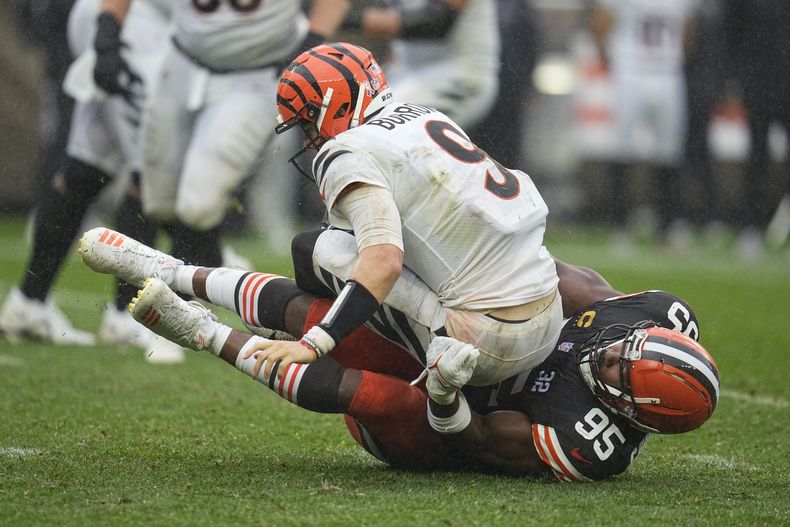 Joe Burrow (9), quarterback de los Bengals de Cincinnati, es capturado por Myles Garrett (95), defensive end de los Browns de Cleveland, durante la segunda mitad del partido de la NFL, el domingo 10 de septiembre de 2023, en Cleveland. (AP Photo/David Richard)