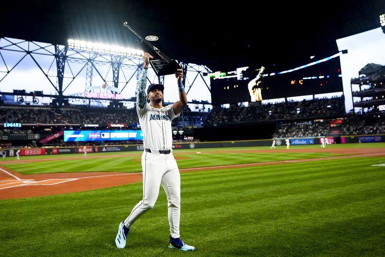 El jardinero central de los Marineros de Seattle Julio Rodríguez sostiene el trofeo al toletero de plata de la temporada pasada durante el Día Inaugural en el encuentro ante los Medias Rojas de Boston el jueves 28 de marzo del 2024. (AP Foto/Lindsey Wasson)