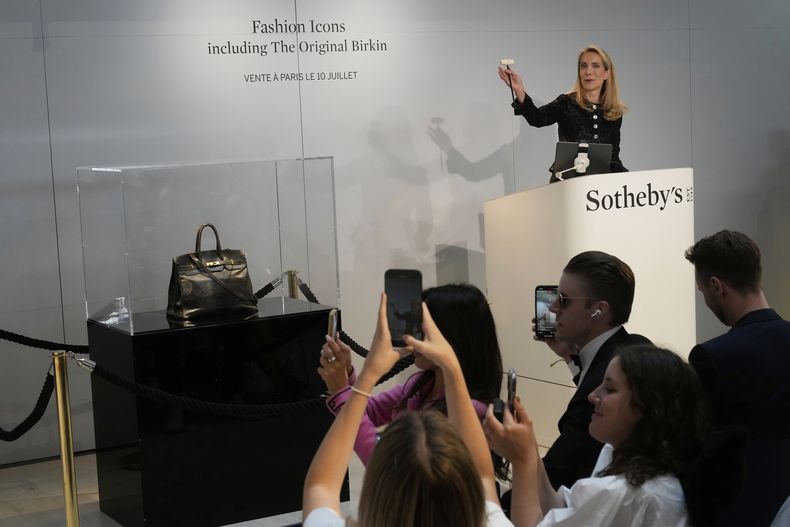 La funcionaria de subastas Aurélie Vandevoorde hace un gesto mientras el bolso Birkin original creado por Hermès para Jane Birkin se vendió en una subasta por 7 millones de euros o 8,2 millones de dólares, el jueves 10 de julio de 2025 en París. (AP Photo/Michel Euler)
