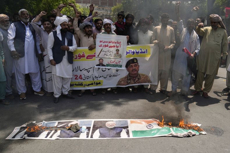 Un grupo de personas protestan quemando un cartel del primer ministro indio Narendra Modi y una bandera india en Lahore, Pakistán, el 27 de abril de 2025. (AP foto/K.M. Chaudary)