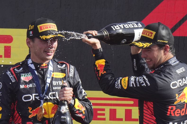 El piloto mexicano Sergio Pérez baña a Max Verstappen, su compañero en el equipo Red Bull, durante la celebración tras el 1-2 en el Gran Premio de Italia, el 3 de septiembre de 2023, en Monza. (AP Foto/Luca Bruno)