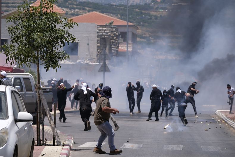 Manifestantes drusos se enfrentan con la policía israelí que les lanzó gas lacrimógeno durante una protesta, en las Alturas del Golán, el miércoles 21 de junio de 2023. (AP Foto/Fadi Amun)