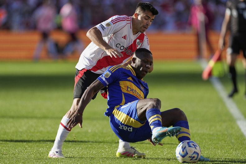 Luis Advíncula, de Boca Juniors, protege la pelota de Marcos Acuña de River Plate durante un partido del torneo local en Buenos Aires, Argentina, el domingo 27 de abril de 2025. (AP Photo/Gustavo Garello)