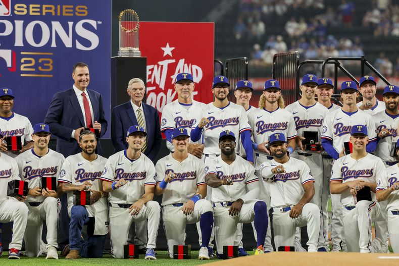 Los jugadores, coaches y dueños de los Rangers de Texas posan tras recibir sus anillos de campeonos de la Serie Mundial, el 30 de marzo de 2024, en Arlington, Texas. (AP Foto/Gareth Patterson)