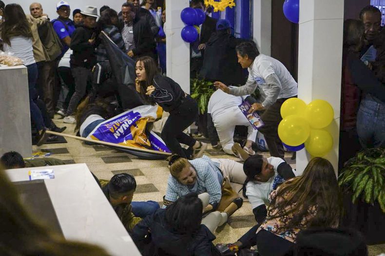 Simpatizantes del candidato presidencial Fernando Villavicencio se ponen a cubierto tras el ataque a tiros que mató al aspirante a la salida de un mítin electoral en un colegio en Quito, Ecuador, el miércoles 9 de agosto de 2023. (API vía AP)
