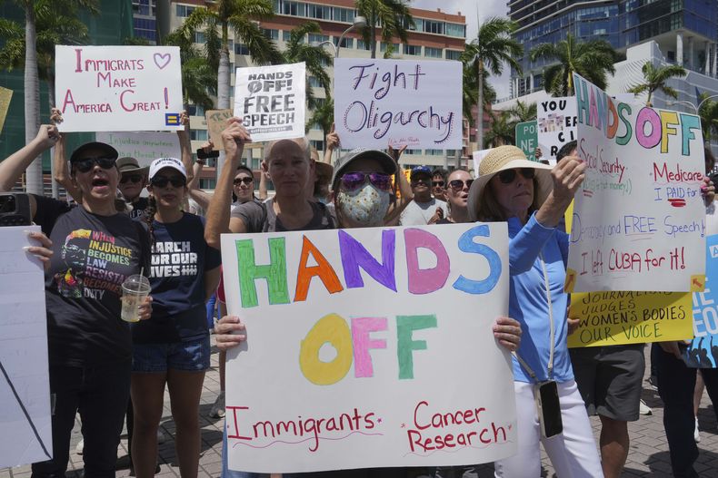Manifestantes llevan carteles y corean consignas en protesta contra las políticas del presidente Donald Trump y Elon Musk el sábado 5 de abril de 2025, en Miami. (AP Foto/Marta Lavandier)