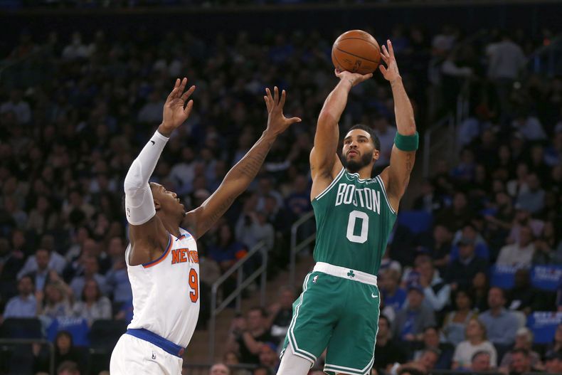Jayson Tatum, alero de los Celtics de Boston, dispara frente a RJ Barrett, de los Knicks de Nueva York, en el encuentro del miércoles 25 de octubre de 2023 (AP Foto/John Munson)