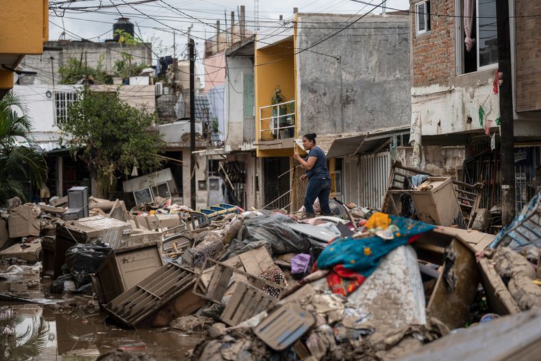 Una mujer camina sobre los escombros y basura acumulados tras las recientes lluvias torrenciales en una calle de Poza Rica, el miércoles 15 de octubre de 2025, en el estado de Veracruz, México. (AP Foto/Félix Márquez)