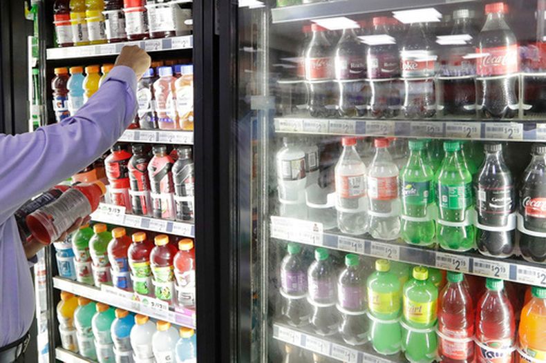 ARCHIVO – El propietario de una tienda busca en el interior de un refrigerador de bebidas en su tienda de Kent, Washington, el 1 de octubre de 2018. (AP Foto/Elaine Thompson, Archivo)