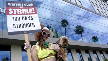 Phoebe Price lleva a su perro Arnold junto con un cartel en una protesta frente a los estudios de Netflix el miércoles 9 de agosto de 2023 en Los Ángeles. La huelga de guionistas de Hollywood alcanzó hoy la marca de los 100 días, las industrias del cine y la televisión de Estados Unidos siguen paralizadas por huelgas de guionistas y actores. (Foto AP/Chris Pizzello)