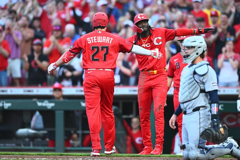 Sal Stewart de los Rojos de Cincinnati, a la izquierda, celebra tras su jonrón de tres carreras con su compañero Elly de la Cruz, el segundo desde la izquierda, durante la primera entrada de un partido de béisbol contra los Tigres de Detroit en Cincinnati, el sábado 25 de abril de 2026. (AP Foto/Ben Jackson)
