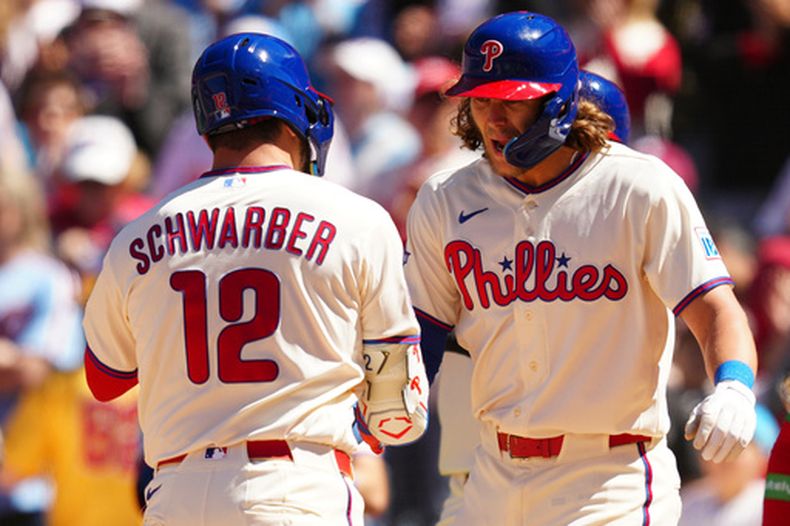Kyle Schwarber (12), de los Filis de Filadelfia, celebra su jonrón de tres carreras contra el lanzador de los Diamondbacks de Arizona, Brandon Pfaadt, junto a Alec Bohm, a la derecha, durante la tercera entrada de un partido de béisbol, el sábado 11 de abril de 2026, en Filadelfia. (Foto AP/Derik Hamilton)