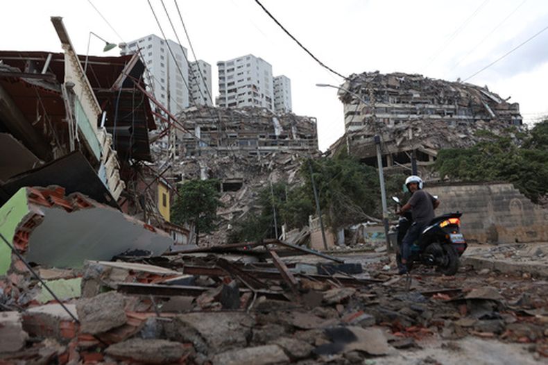 Un motociclista pasa junto a edificios dañados por un terremoto, el jueves 25 de junio de 2026, en Catia La Mar, Venezuela. (AP Foto/Pedro Mattey)