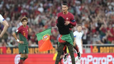 Un individuo que irrumpió en la cancha abraza al astro portugués Cristiano Ronaldo durante el partido contra Bosnia y Herzegovina por las eliminatorias de la Eurocopa, el sábado 17 de junio de 2023, en Lisboa. (AP Foto/Armando Franca)