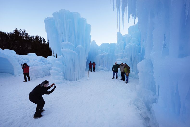 Visitantes posan para una foto en el primer día de la exhibición Ice Castles, el viernes 10 de enero de 2025, en North Woodstock, Nueva Hampshire. (AP foto/Robert F. Bukaty)