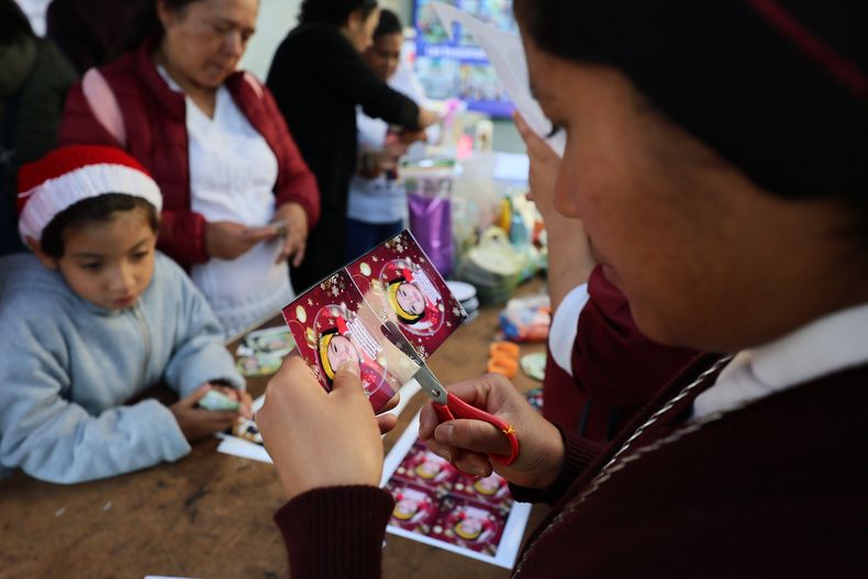 La hermana María Elena recorta una fotografía de una niña desaparecida para pegarla en un adorno navideño para colgarlo en el Árbol de la Esperanza, durante un evento organizado por la diócesis de Ecatepec en la Iglesia del Sagrado Corazón de San Cristóbal en Ecatepec, Estado de México, el lunes 17 de noviembre de 2025. (AP Foto/Ginnette Riquelme)