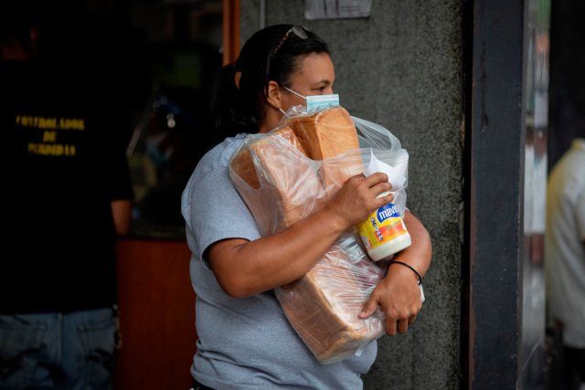Una mujer carga sus compras mientras sale de un supermercado, el 14 de abril de 2021, en Caracas (Venezuela). EFE/RAYNER PEÑA R.