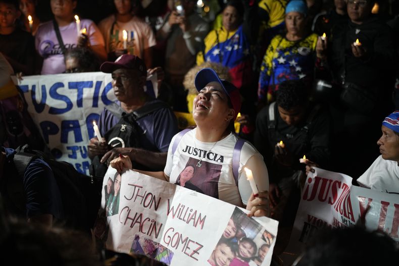 ARCHIVO - Personas con fotos de sus familiares que fueron deportados de Estados Unidos a una prisión en El Salvador, por ser presuntos miembros de la pandilla Tren de Aragua, lloran y rezan frente a la embajada de El Salvador en Caracas, Venezuela, el 2 de abril de 2025. (AP Foto/Ariana Cubillos, Archivo)