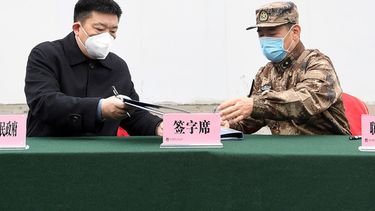 Zhou Xianwang, izquierda, alcalde de Wuhan, intercambia documentos con Bai Zhongbin, derecha, subcomandante en jefe de la Fuerza de Apoyo Logístico Conjunto del Ejército Popular de Liberación de China, el 2 de febrero de 2020, durante una ceremonia de entrega en el hospital de campaña temporal de Huoshenshan, en Wuhan, provincia de Hubei, centro de China. (Chinatopix vía AP)