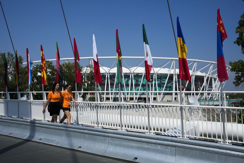 Voluntarias caminan frente al Centro Nacional de Atletismo, previo al Mundial de atletismo, el miércoles 16 de agosto de 2023, en Budapest. (AP Foto/Ashley Landis)