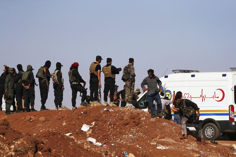 Una caravana de ambulancias y autobuses llegan a un control de carretera en el pueblo de Busra al-Harir, en el sur de Siria, camino de la provincia de Sweida, mientras las fuerzas de seguridad mantienen un perímetro para impedir a combatientes beduinos entrar en la provincia, el martes 22 de julio de 2025. (AP Foto/Omar Sanadiki)