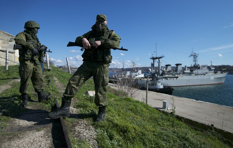 ARCHIVO - Soldados rusos montan guardia en un muelle en que dos embarcaciones navales ucranianas se encuentran atracadas, en Sebastopol, en la península de Crimea, el 4 de marzo de 2014. (AP Foto, Archivo)