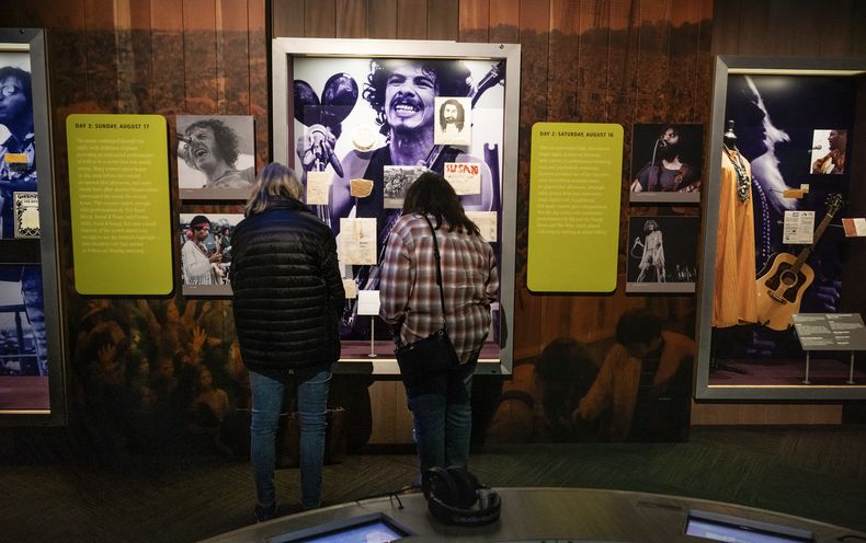 Personas miran mensajes originales del Árbol de los Mensajes, un árbol del legendario festival de Woodstock de 1969 utilizado por los asistentes al concierto como una especie de tablero de mensajes, en exhibición en el Museo de Bethel Woods, el miércoles 25 de septiembre de 2024, en Bethel, Nueva York. (Foto AP/Craig Ruttle)