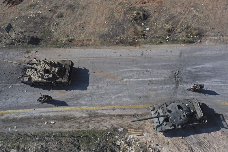 Insurgentes sirios montan en motocicleta entre tanques abandonados del Ejército sirio en una carretera a las afueras de Hama, Siria, el martes 3 de diciembre de 2024. (AP Foto/Ghaith Alsayed)