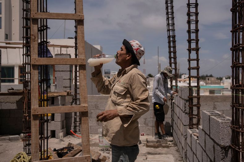 ARCHIVO - Jorge Moreno bebe agua saborizada para sobrellevar la ola de calor durante su jornada laboral en una obra de construcción en Veracruz, México, el 17 de junio de 2024. (Foto AP/Félix Márquez, archivo)