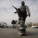 Un rebelde sirio sobre un busto de fallecido presidente sirio Hafez Assad en Damasco el 8 de diciembre del 2024. (AP foto/Hussein Malla)
