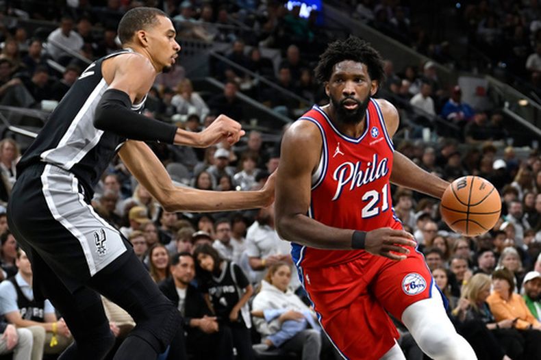 Joel Embiid (21) de los 76ers de Filadelfia penetra hacia la canasta ante Victor Wembanyama (izquierda) de los Spurs de San Antonio, el lunes 6 de abril de 2026. (AP Foto/Darren Abate)