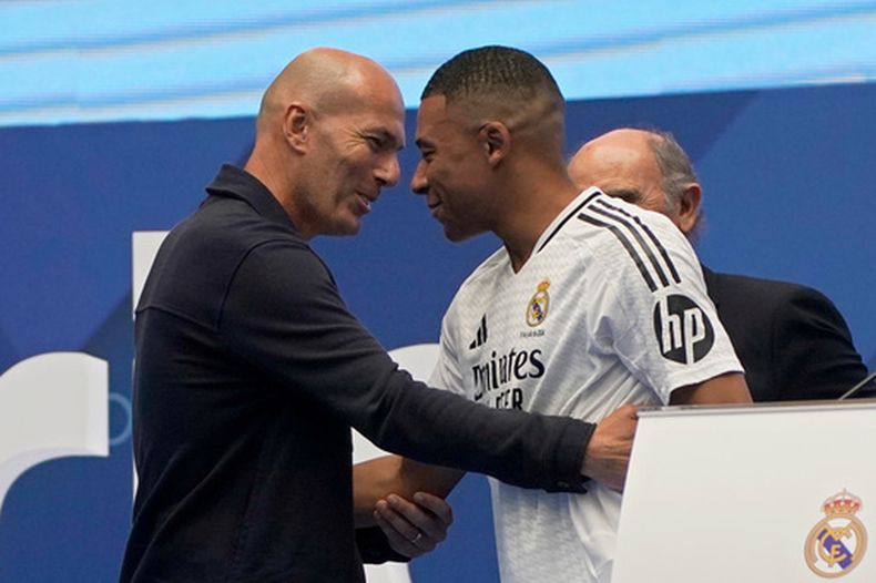 ARCHIVO - El exfutbolista francés Zinedine Zidane, a la izquierda, abraza al futbolista francés Kylian Mbappe al ser presentado a los aficionados como nuevo jugador del Real Madrid en Madrid, el 16 de julio de 2024. (AP Foto/Andrea Comas, Archivo)