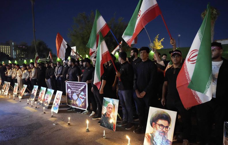 Manifestantes se congregan frente a la embajada de Irán portando velas y banderas iraníes durante una protesta en honor a los generales de las fuerzas armadas iraníes, científicos nucleares y sus familiares que murieron en ataques israelíes, en Bagdad, Irak, el sábado 28 de junio de 2025. (Foto AP/Hadi Mizban)