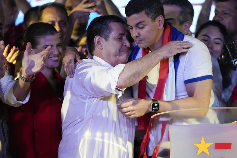 Santiago Peña, candidato presidencial del gobernante Partido Colorado, a la derecha, abraza al expresidente Horacio Cartes tras el cierre de votaciones que le dieron un amplia victoria en las elecciones generales, en Asunción, Paraguay, el domingo 30 de abril de 2023. (AP Foto/Jorge Sáenz)