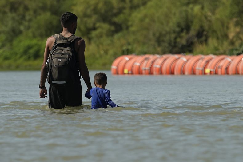 Migrantes cerca de la barrera flotante en el río Bravo cerca de Eagle Pass, Texas, el 1 de agosto de 2023. (Foto AP /Eric Gay)