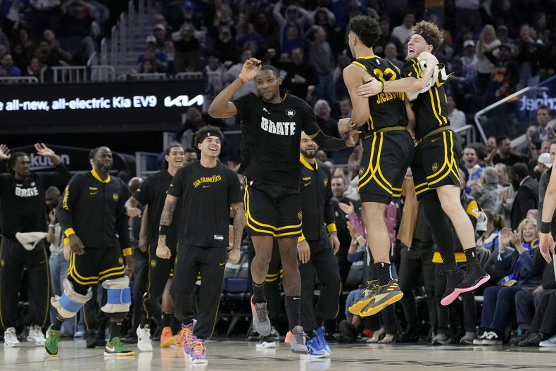 Jonathan Kuminga (centro), alero de los Warriors de Golden State, festeja con Trayce Jackson Davis y Brandin Podziemski en el encuentro del miércoles 6 de marzo de 2024 (AP Foto/Jeff Chiu)