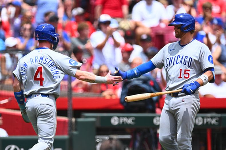 Pete Crow-Armstrong, de los Cachorros de Chicago (izquierda), celebra con Carson Kelly (derecha) tras anotar una carrera impulsada por un doble de Alex Bregman durante la primera entrada de un partido de béisbol contra los Rojos de Cincinnati, en Cincinnati, el domingo 12 de julio de 2026. (Foto AP/Ben Jackson)