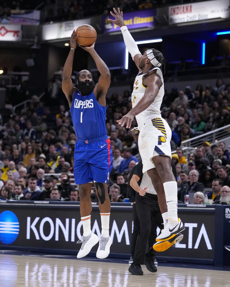 James Harden, base de los Clippers de Los Ángeles, dispara frente a Buddy Hield, de los Pacers de Indiana, en el duelo del lunes 18 de diciembre de 2023 (AP Foto/Michael Conroy)