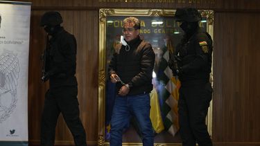 ARCHIVO - La policía escolta al exdirector antidrogas de la policía boliviana, coronel Maximiliano Dávila, mientras es presentado a la prensa en una oficina de comando de la policía boliviana después de ser arrestado acusado de estar vinculado con una red de narcotráfico en La Paz, Bolivia, domingo 23 de enero de 2022. (AP Foto/Juan Karita, Archivo)