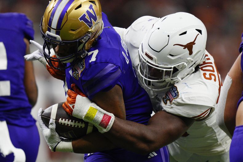 Dillon Johnson, de Washington, acarrea el balón mientras Barryn Sorrell, de Texas, intenta derribarlo en el Sugar Bowl, el lunes 1 de enero de 2024 (AP Foto/Jacob Kupferman)