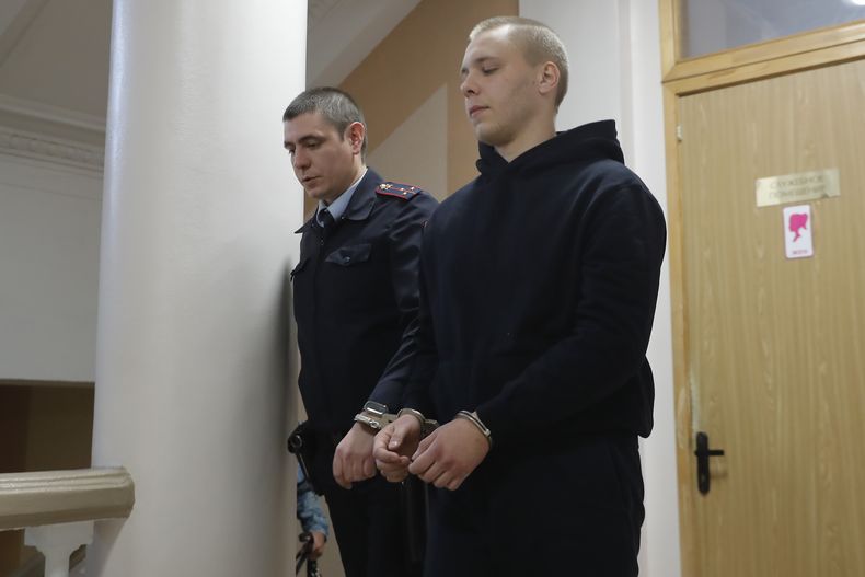 Nikita Zhuravel, a la derecha, es escoltado por la policía a una sala judicial antes de una vista en un caso de traición en Volgogrado, Rusia, el jueves 14 de noviembre de 2024. (AP Foto)