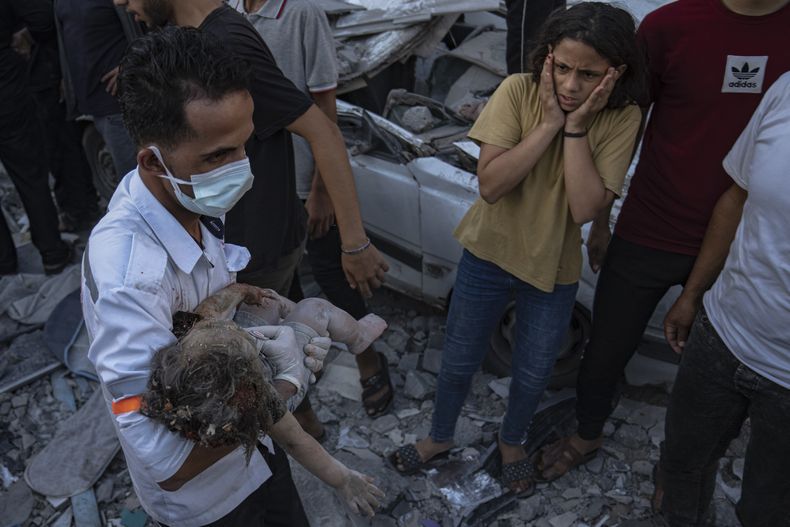 Una niña palestina reacciona al ver a un niño pequeño sacado de entre los escombros de un edificio luego de un ataque aéreo israelí sobre Jan Yunis, en la Franja de Gaza, el 21 de octubre de 2023. (AP Foto/Fatima Shbair)