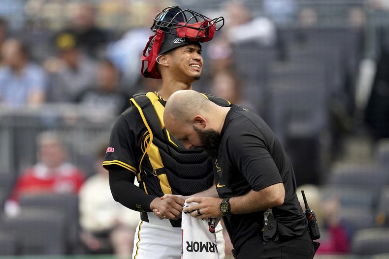 El catcher de los Piratas de Pittsburgh Endy Rodríguez es revisado por un entrenador tras lesionarse en el encuentro ante los Nacionales de Washington el lunes 14 de abril del 2025. (AP Foto/Matt Freed)